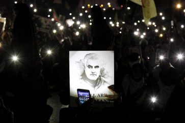 A Shiite Muslim illuminates a portrait of Iranian Revolutionary Guard Gen. Qassem Soleimani, with light from a mobile phone, during a rally to condemn his killing in Iraq by a U.S. airstrike, in Karachi, Pakistan, Sunday, Jan. 5, 2020. Iran has vowed "harsh retaliation" for the U.S. airstrike near Baghdad's airport that killed Tehran's top general and the architect of its interventions across the Middle East, as tensions soared in the wake of the targeted killing. (AP Photo/Ikram Suri)