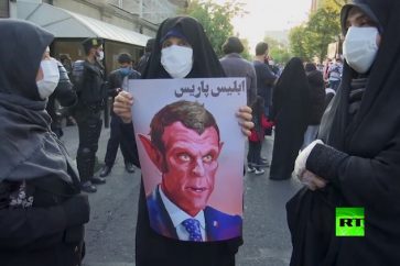Un portrait caricaturiste, représentant Macron sur lequel est inscrit 'le Satan de Paris', brandi par une manifestante iranienne à Téhéran