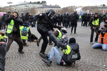 A police officer kicks a protester during an anti-government demonstration called by the "Yellow Vest" (Gilets Jaunes) movement on January 12, 2019, on the Place de l'Etoile, in Paris. - Thousands of anti-government demonstrators marched in cities across France on January 12 in a new round of "yellow vest" protests against the president, accused of ignoring the plight of millions of people struggling to make ends meet. (Photo by LUDOVIC MARIN / AFP)