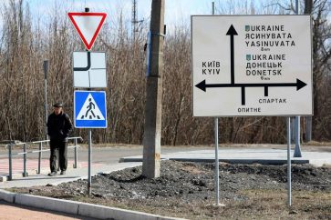 Un homme passe devant un panneau routier dans la ville d’Avdiivka, dans la région de Donetsk, le 21 février 2022. Photo d’illustration | ALEKSEY FILIPPOV/AFP